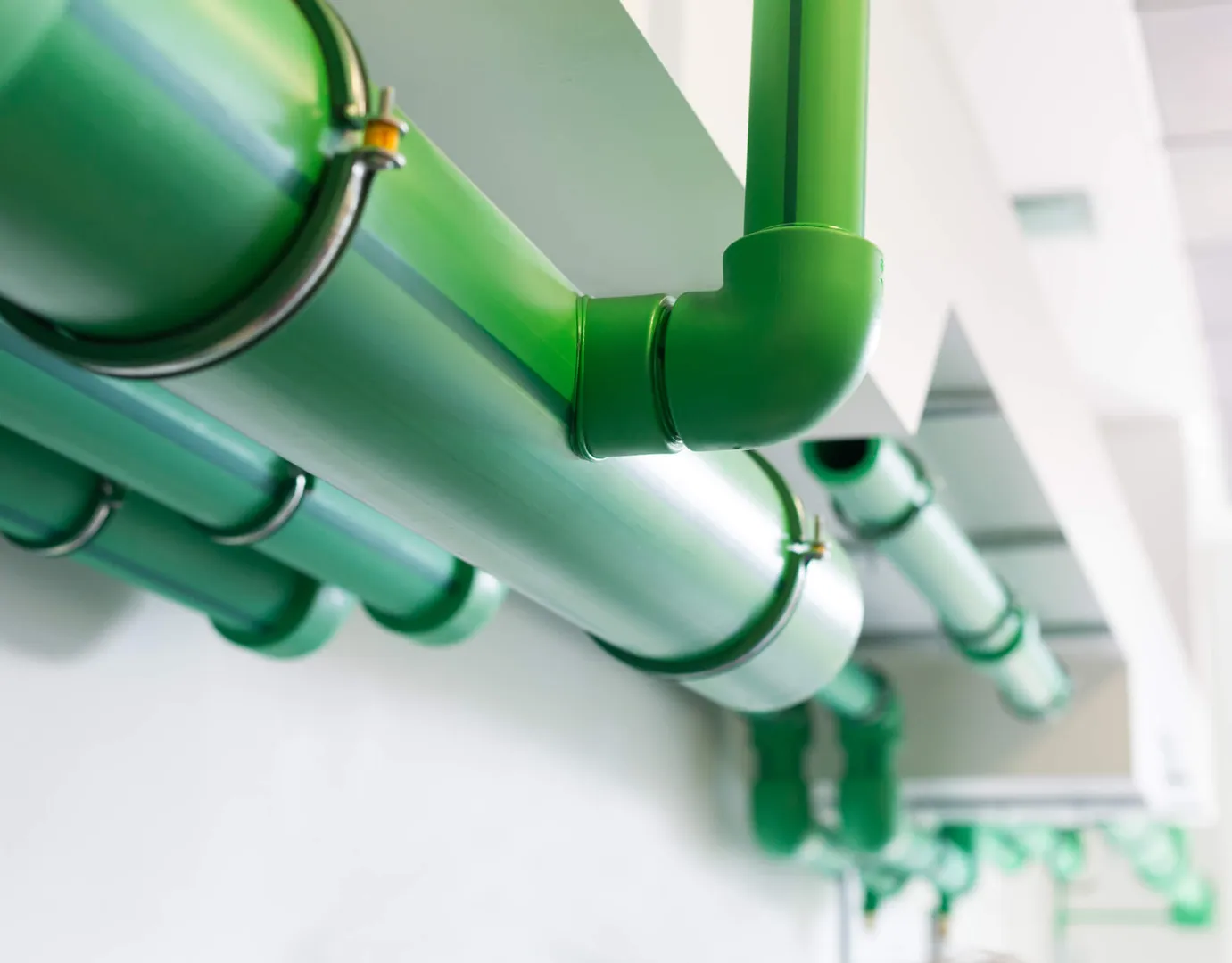 Green pipes under a ceiling.